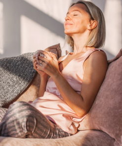 Kobieta relaksująca się z kubkiem w dłoniach w promieniach słońca – ukojenie z olejkiem Spokój K. HEBDA