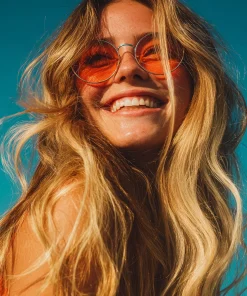 olejek pomarańczowy k. hebda Kobieta w pomarańczowych okularach uśmiecha się w słońcu na tle błękitnego nieba