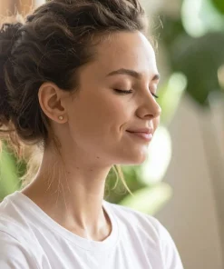 Olejek ylang ylang Klaudyna Hebda w kontekście spokojnej chwili relaksu, przedstawionej przez kobietę z zamkniętymi oczami.