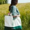 Kobieta w zielonej sukience z dużą torbą bawełnianą Klaudyna Hebda i bukietem kwiatów na łące