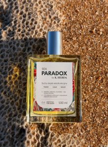 Luksusowy suchy olejek Sea Paradox by K. Hebda na piasku – wielofunkcyjny produkt do twarzy, ciała i włosów.