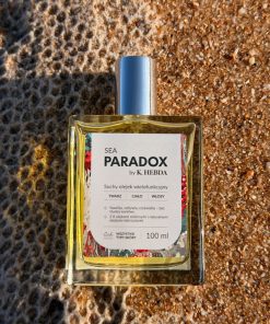 Luksusowy suchy olejek Sea Paradox by K. Hebda na piasku – wielofunkcyjny produkt do twarzy, ciała i włosów.