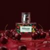 Packshot perfum Cherry Paradox na tle soczystych wiśni