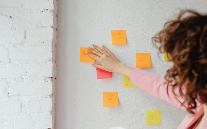 Kobieta przyklejająca karteczki post-it podczas pracy.
