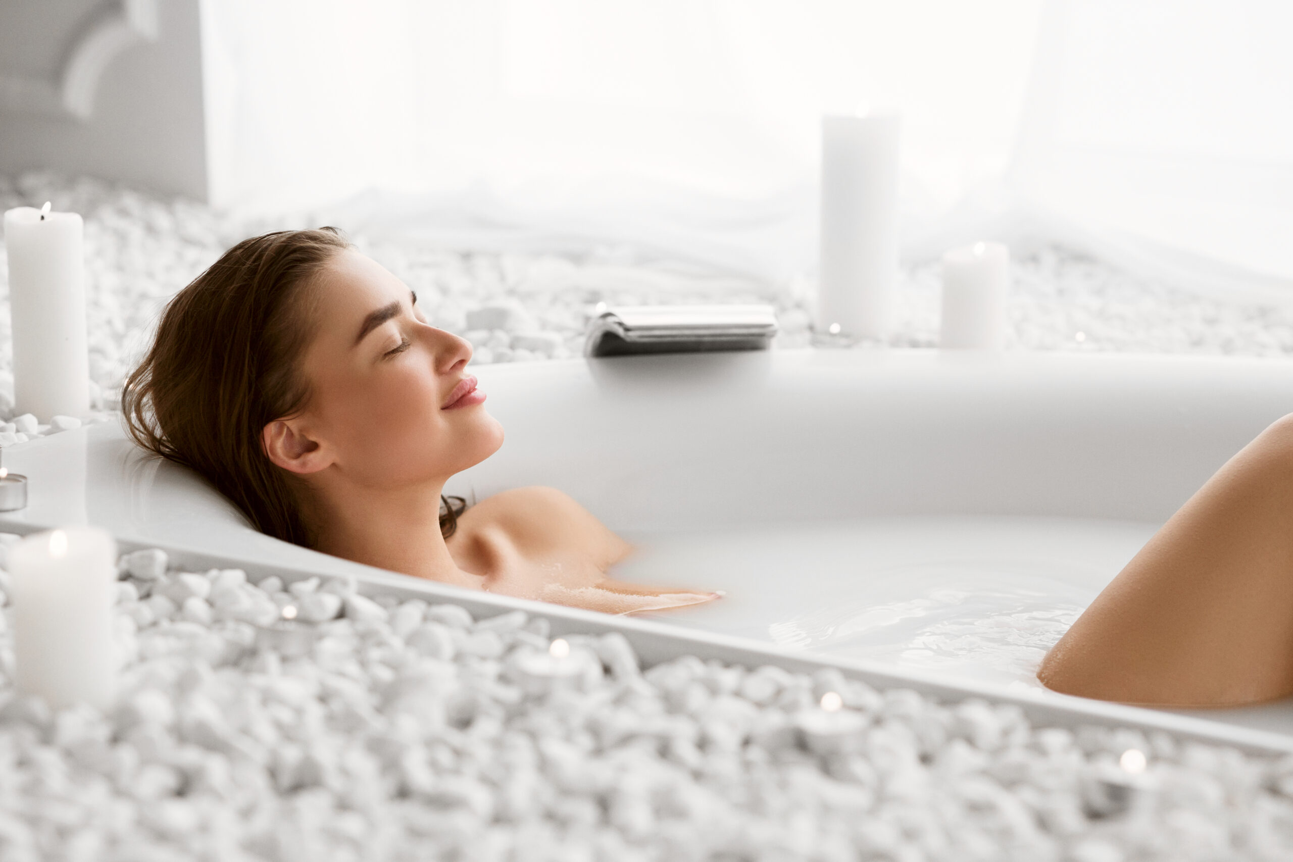 Kobieta relaksująca się w wannie podczas wieczornej kąpieli z solą magnezową, tworzącej atmosferę domowego SPA i regeneracji.