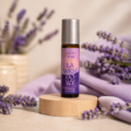 Roll-on Lavandula z naturalnym olejkiem lawendowym na drewnianej podstawce wśród kwiatów lawendy