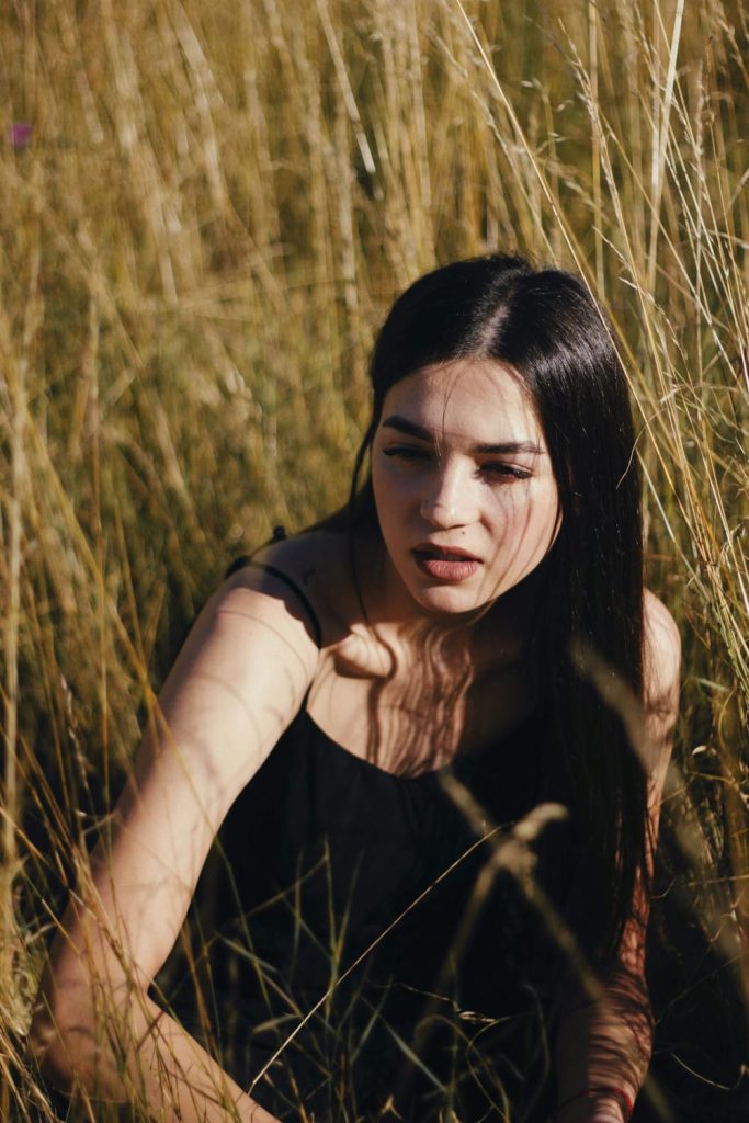 Dziewczyna w wysokiej, gęstej trawie, w której chętnie bytują kleszcze, kiedy są najbardziej aktywne – klaudynahebda.pl