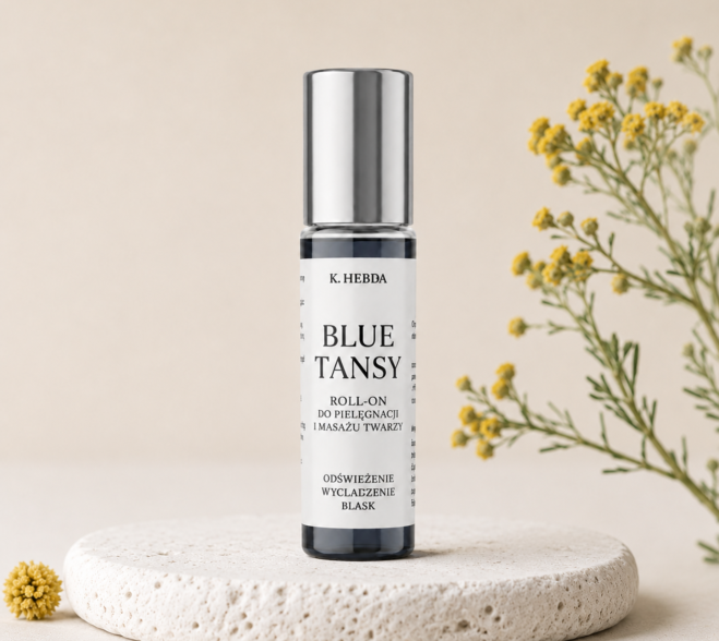 Blue Tansy Roll-On K. Hebda ustawiony na jasnym kamieniu w otoczeniu żółtych kwiatów wrotyczu marokańskiego (Blue Tansy) – kosmetyk do pielęgnacji i masażu twarzy.