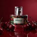 Flakon luksusowych perfum damskich Cherry Paradox by K. Hebda 50 ml w otoczeniu dojrzałych owoców ciemnej wiśni na czerwonym tle.