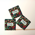 Eleganckie, ciemnozielone opakowania kartonowe z botanicznym motywem liści i wiśni perfum Cherry Paradox by K. Hebda 50 ml.